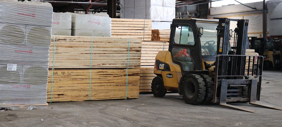 A forklift moving lumber inside the Home Lumber warehouse