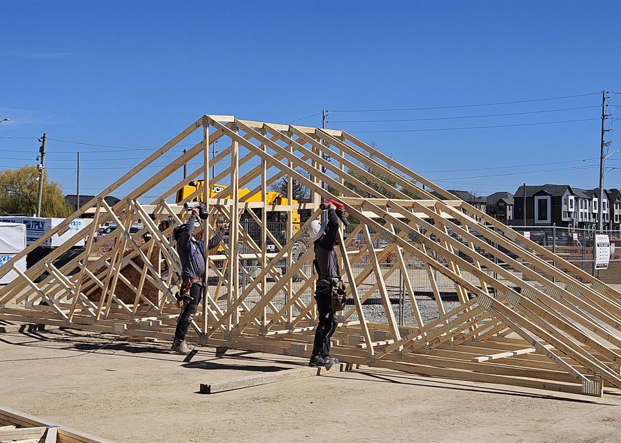 Workers assembling custom roof trusses on site